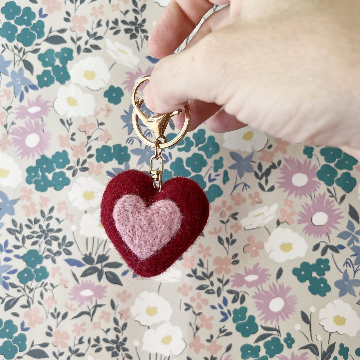 Wool felt heart keychain with gold clip on floral background