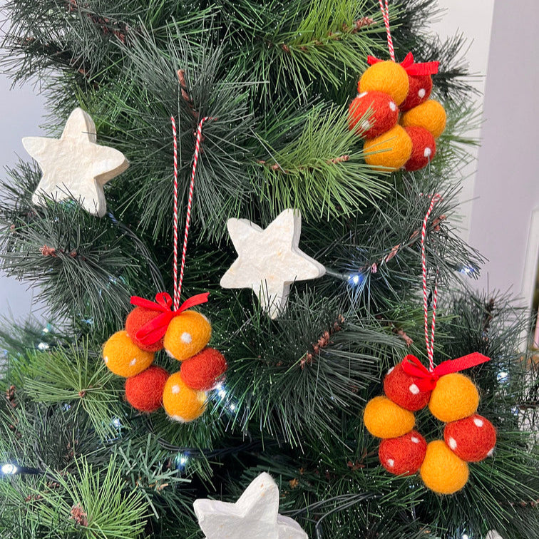 Decorative Christmas ornaments on a tree with red and orange balls and white stars.