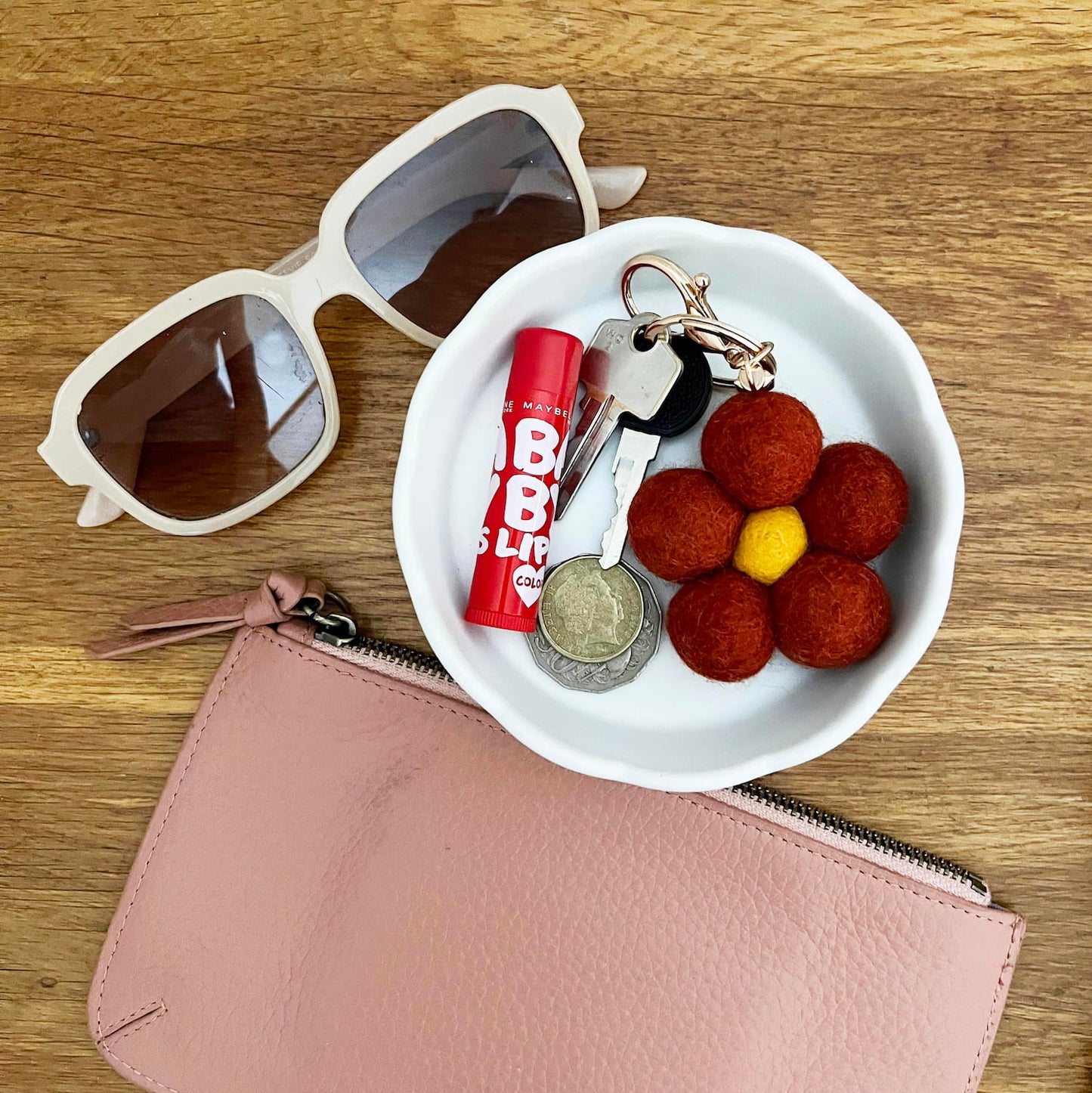 Handmade felt keychain displayed on table with bag accessories