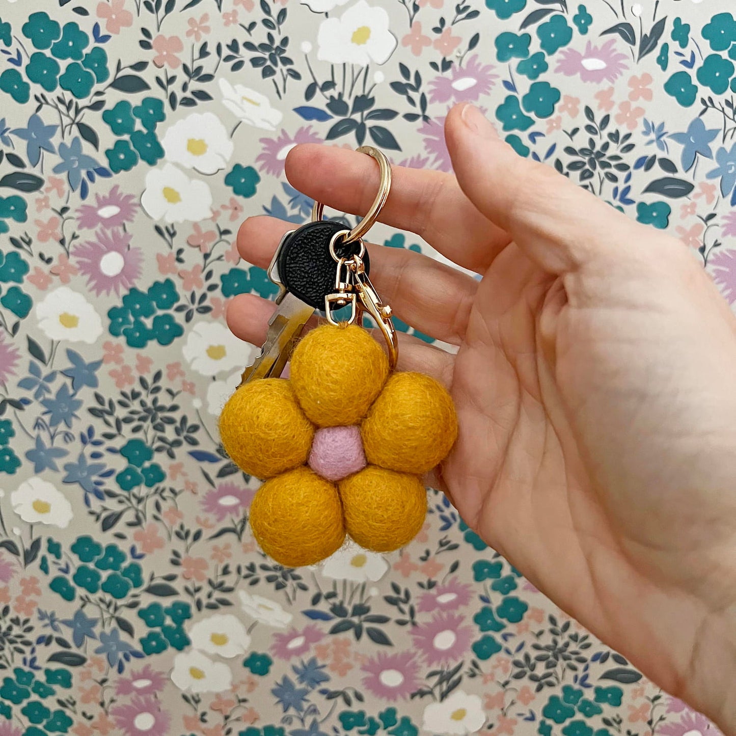 Felt flower keyring with gold clip on floral background