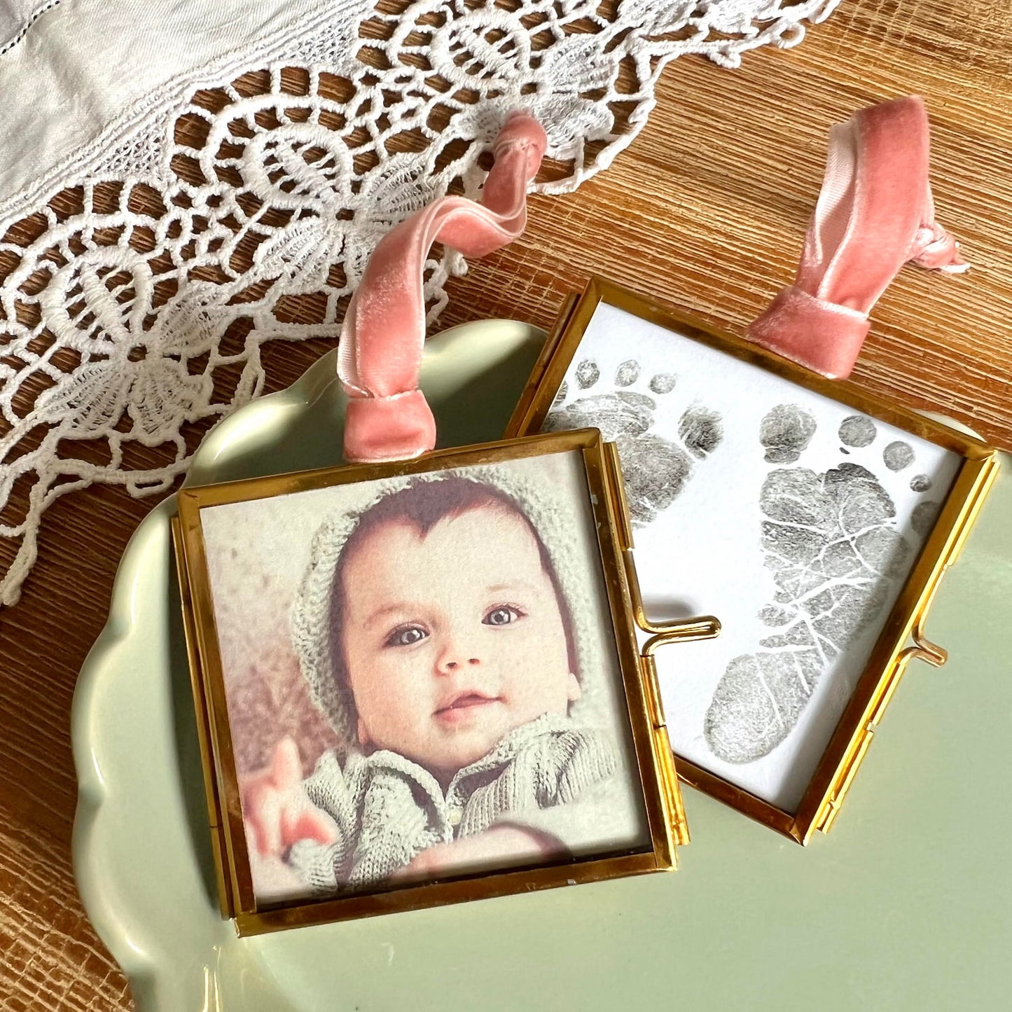 Baby photos and keepsakes displayed inside brass glass frame