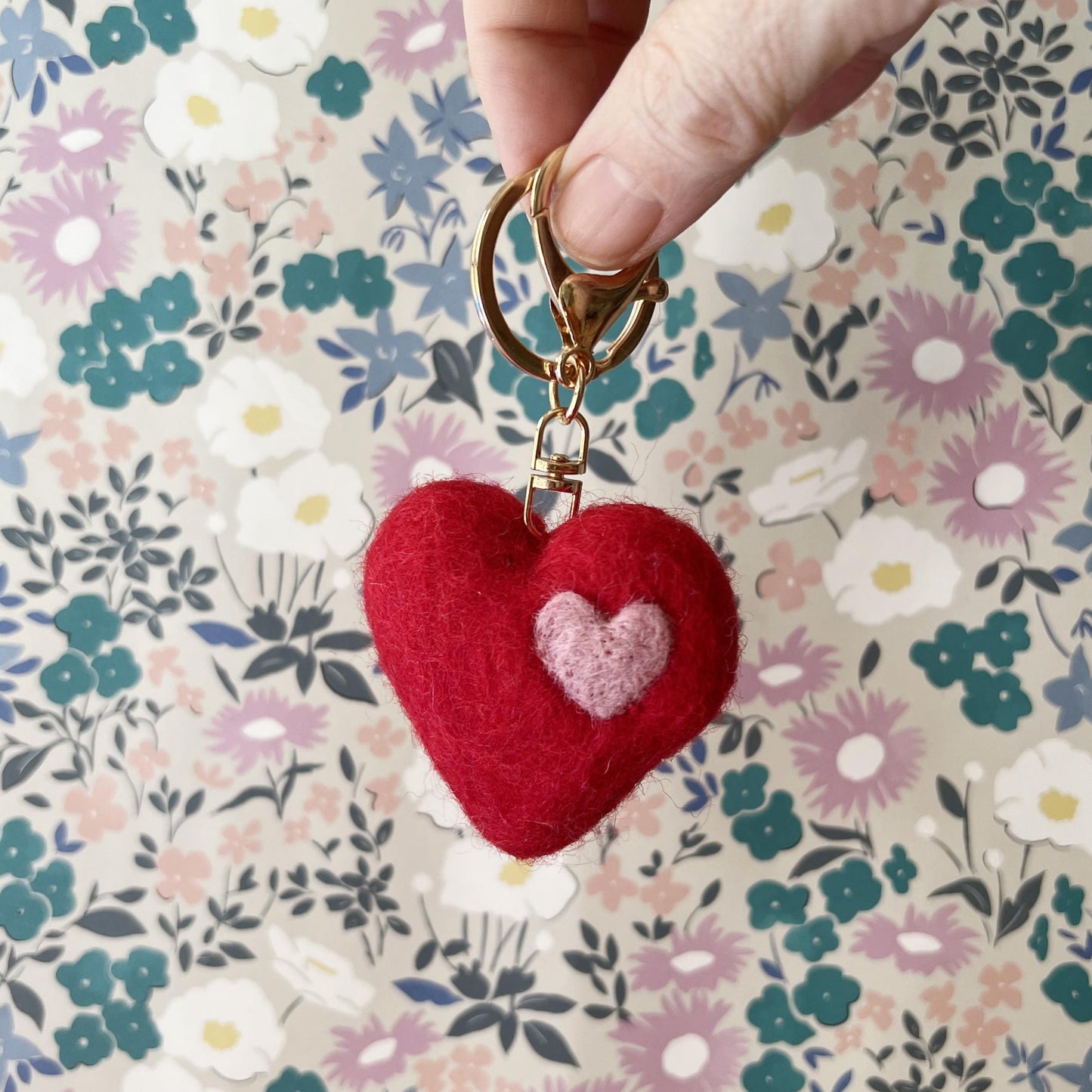 Wool felt heart keychain with gold clip on floral background