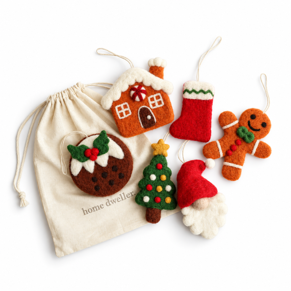 A set of handmade felt Christmas ornaments and a matching drawstring bag. The ornaments include a gingerbread house, a red stocking, a gingerbread man, a pudding with holly, a Christmas tree, and a Santa face, all in warm holiday colors.