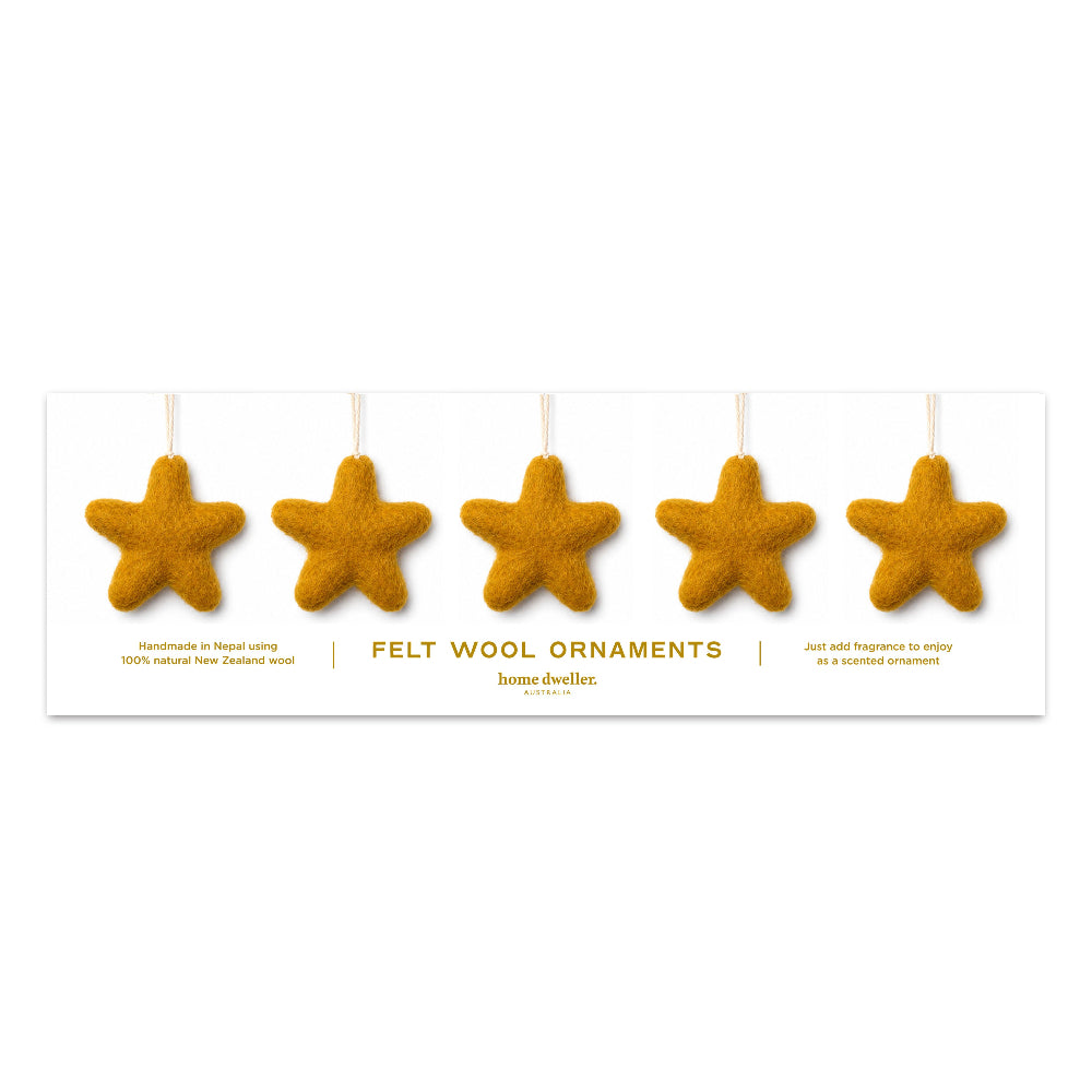Five felt wool star-shaped ornaments in a warm golden-brown color, hanging from white strings above a white product card. The card reads 'FELT WOOL ORNAMENTS' and shows the brand 'home dweller'.