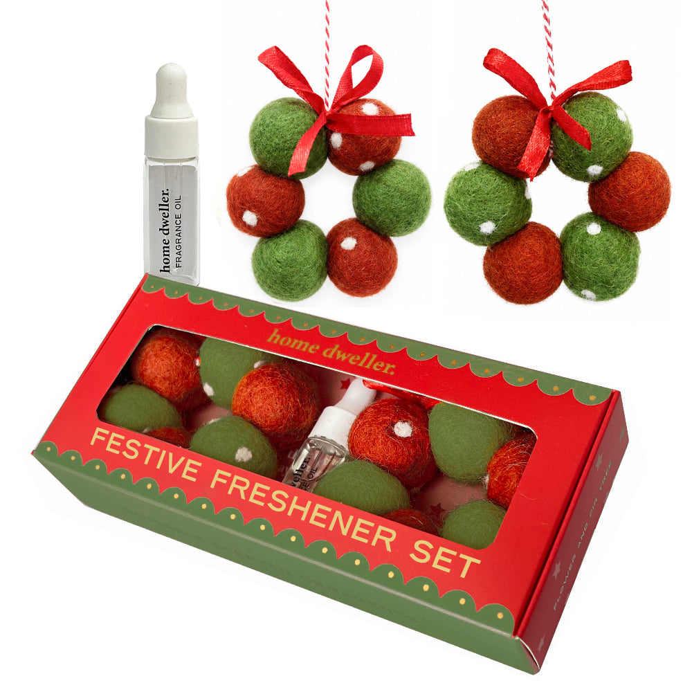 Home Dweller Festive Freshener Set featuring a red and green gift box with a clear window, a small dropper bottle, and two red and green felt ball ornaments with red ribbons on a white background.