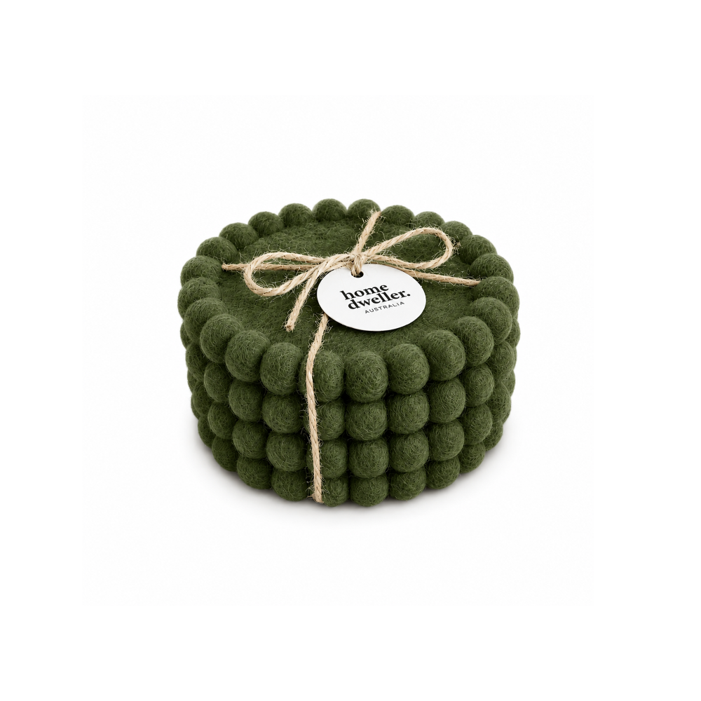 A set of four olive green felt pom-pom coasters bundled together with a twine bow and a round white paper tag that reads 'home dweller'.