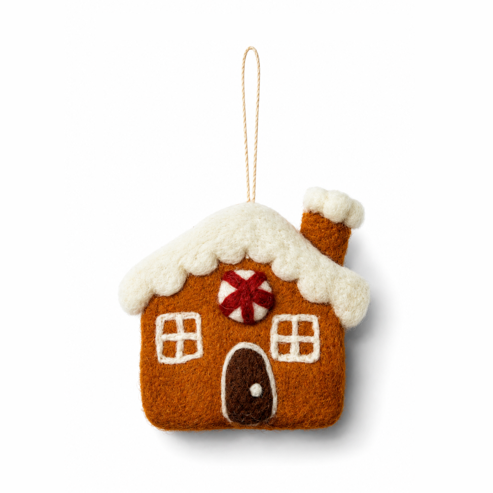 A felted wool gingerbread house ornament in warm brown with white snow-dusted roof and trim, a red-and-white striped candy cane detail, and a hanging loop, shown on a clean white background.