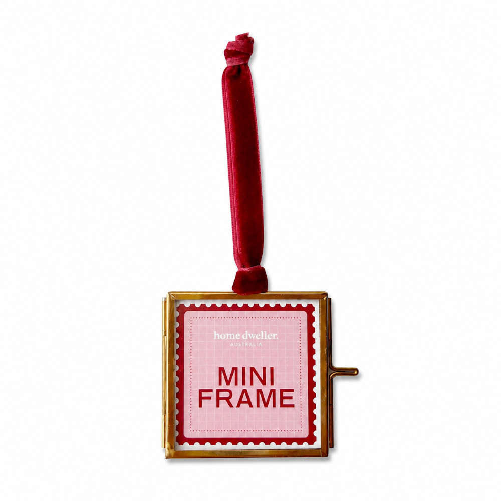 Miniature gold frame with pink label and red ribbon on a white background